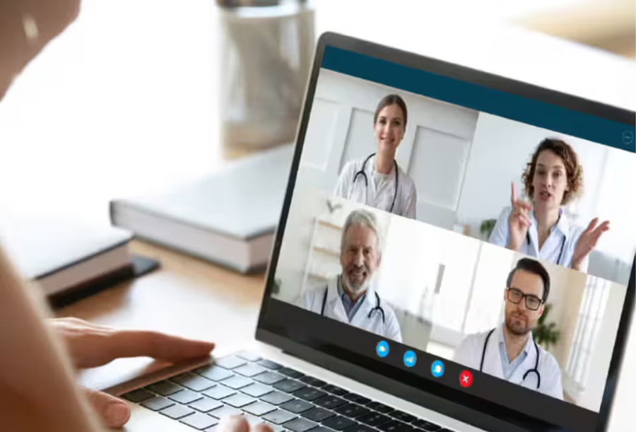 Person participating in a video call with multiple doctors on a laptop.