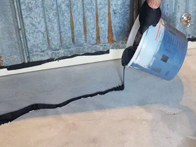 Person in black gloves pouring epoxy on the floor.