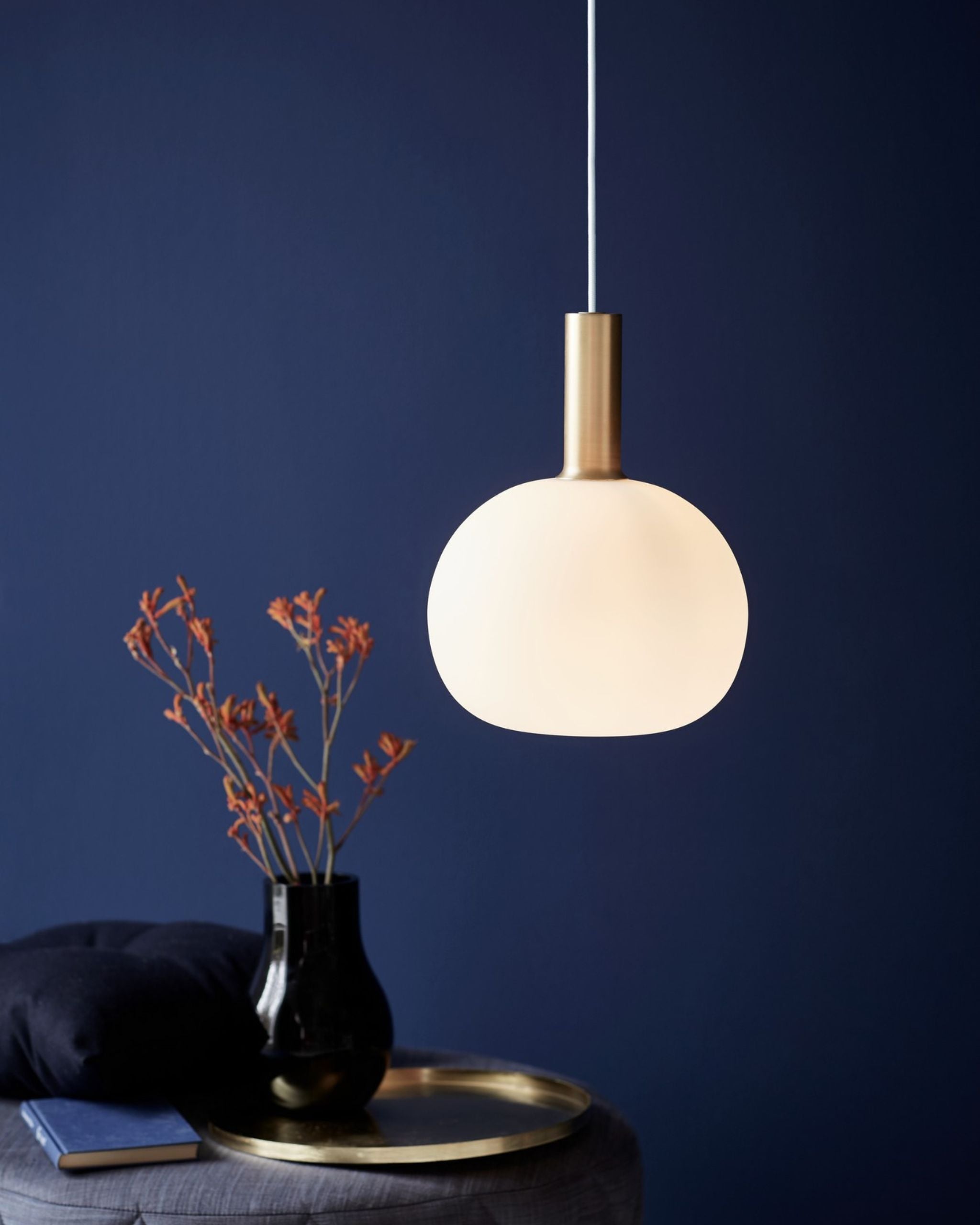Pendant light fixture with a vase and dried plants on a dark blue background