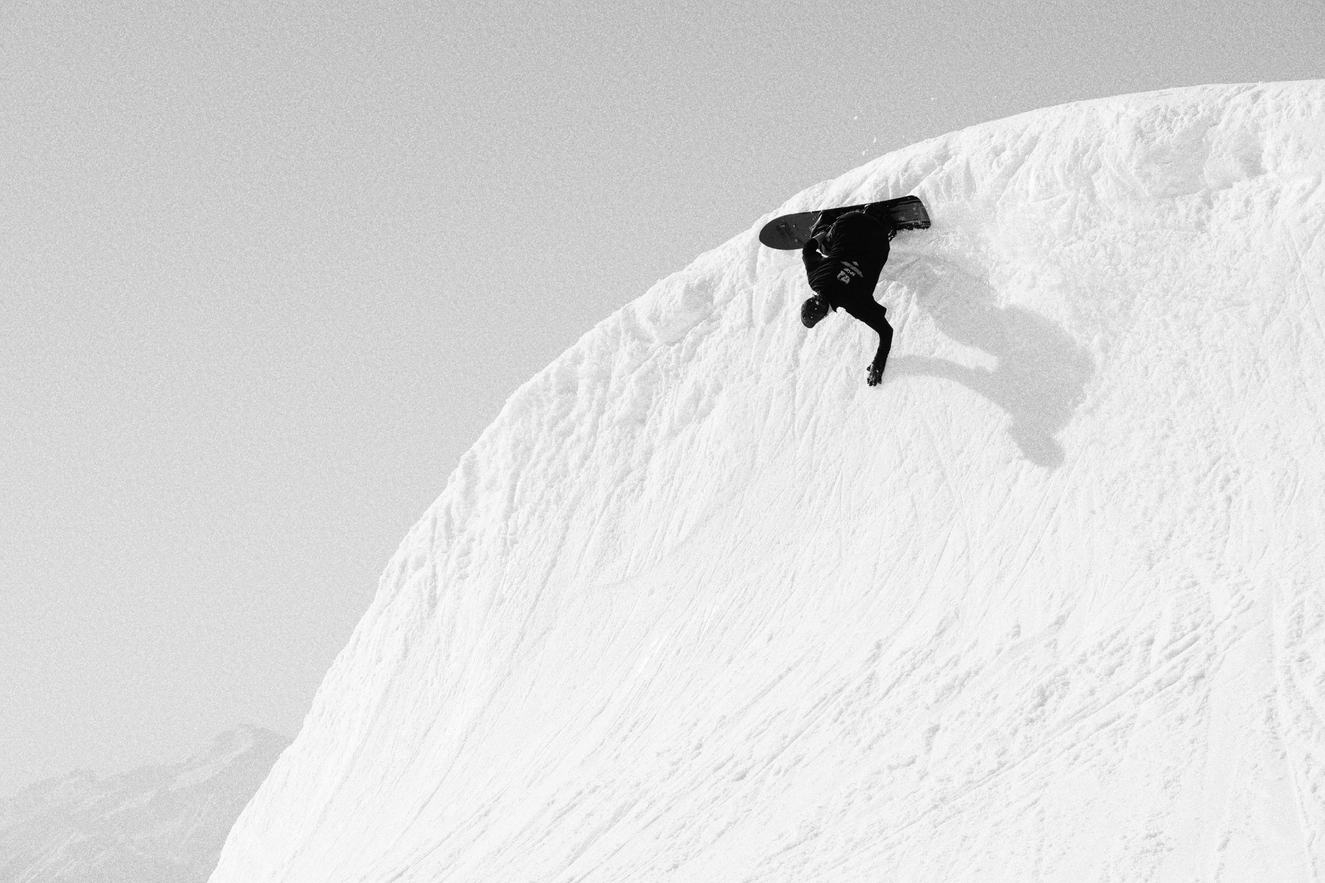 Person snowboarding on a snowy slope in black and white.