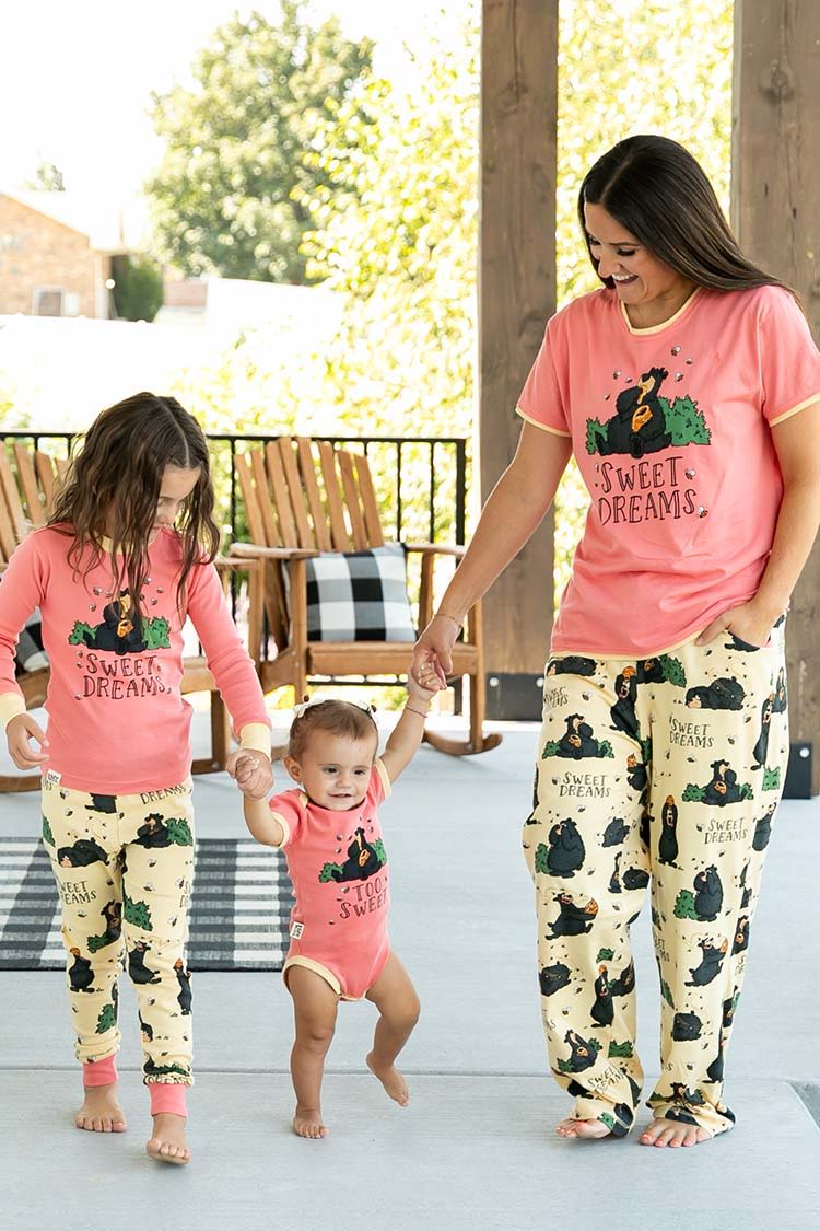 A mother and her two children in matching pajamas on a porch.
