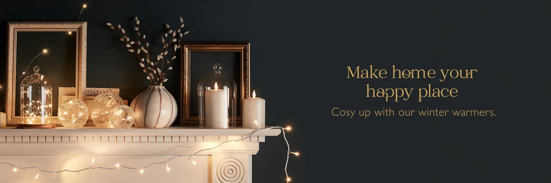Cosy indoor lights and LED candles  on a mantlepiece on a dark navy background