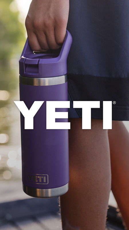 A person holding a purple YETI drink container by the water.