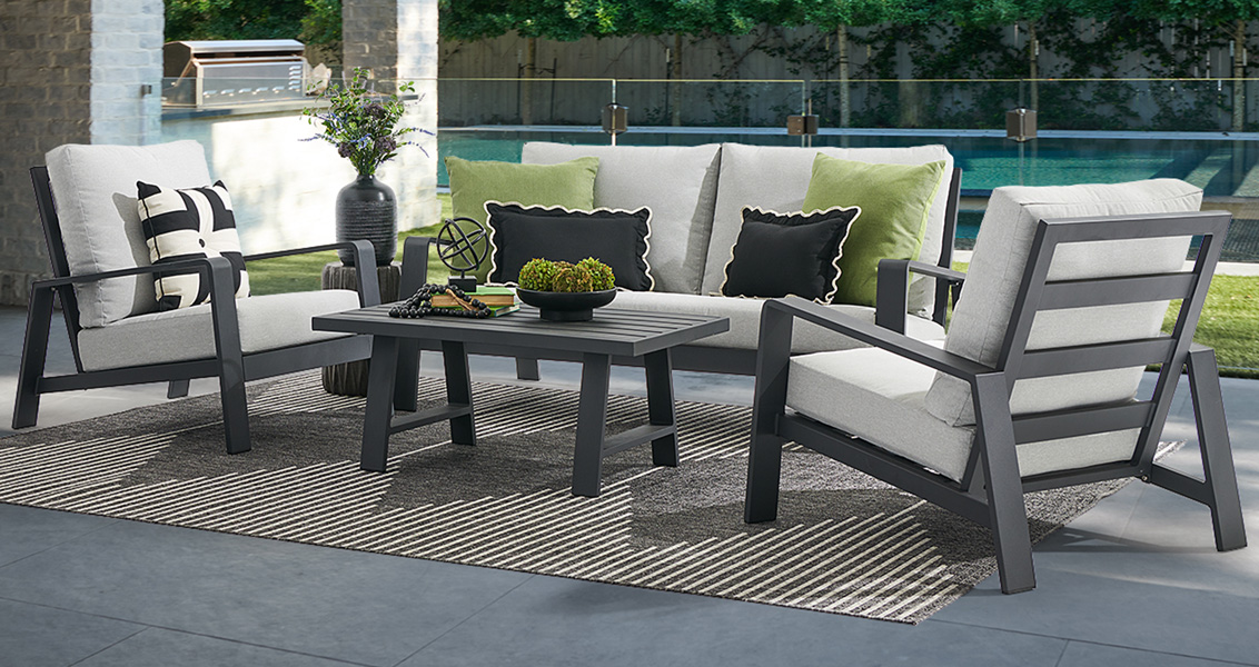 Outdoor seating area with gray furniture, cushions, and a table.