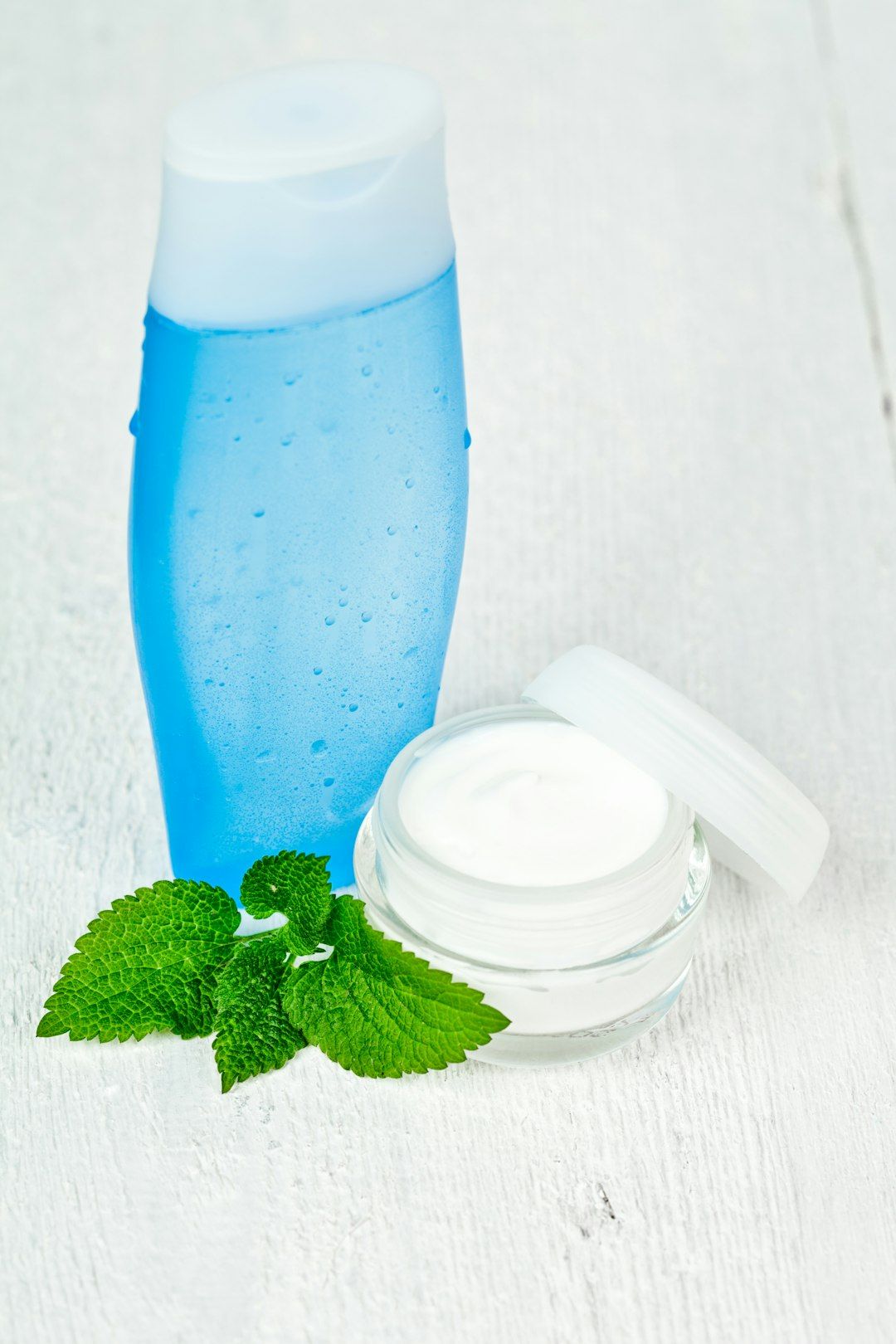 A bottle of lotion next to a mint leaf