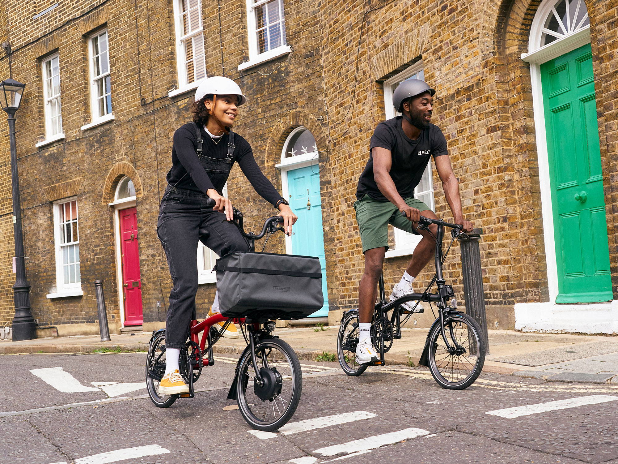 Two people ride Brompton bikes through London