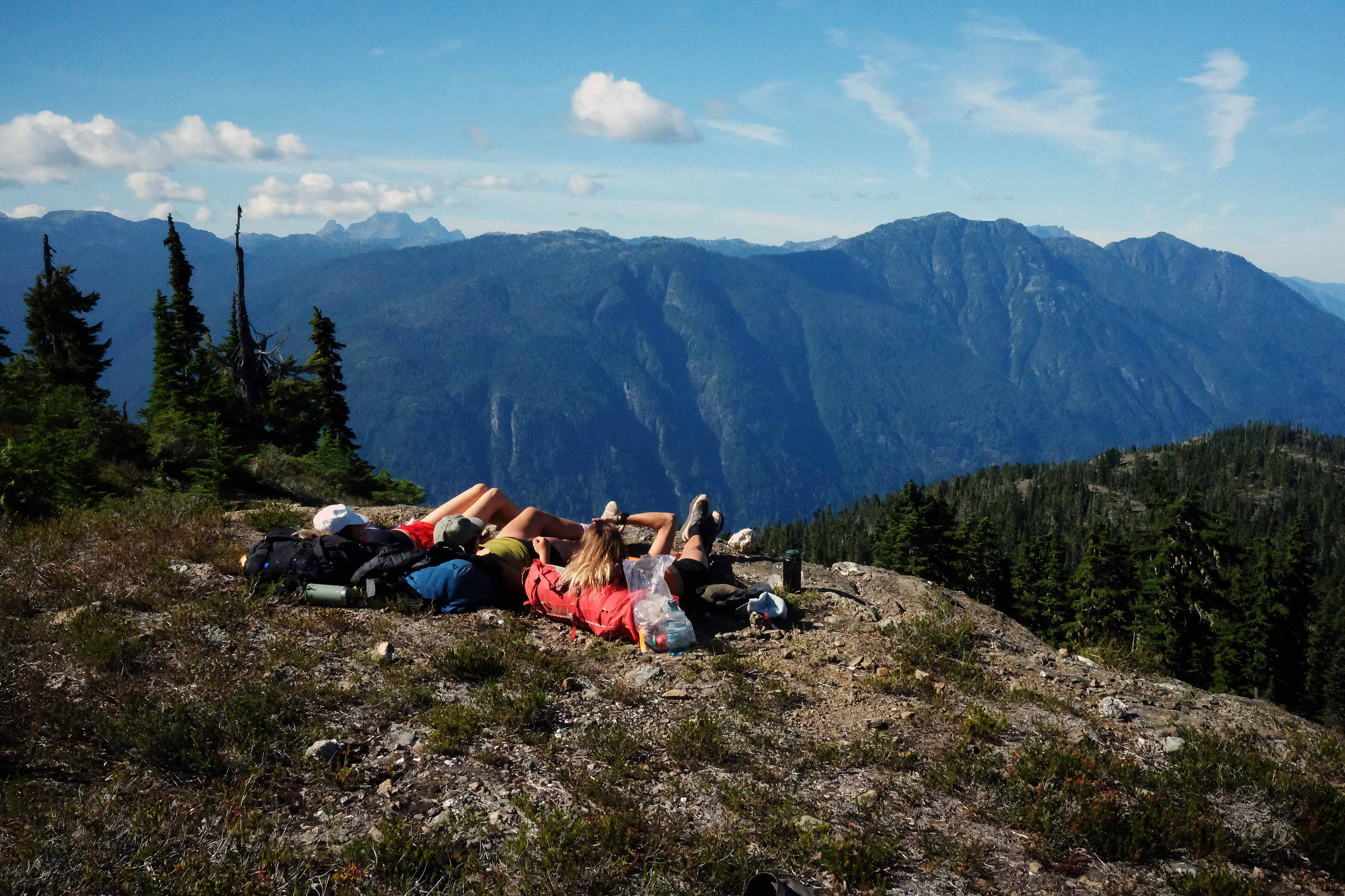 People relaxing on a rocky mountain overlook with scenic views.