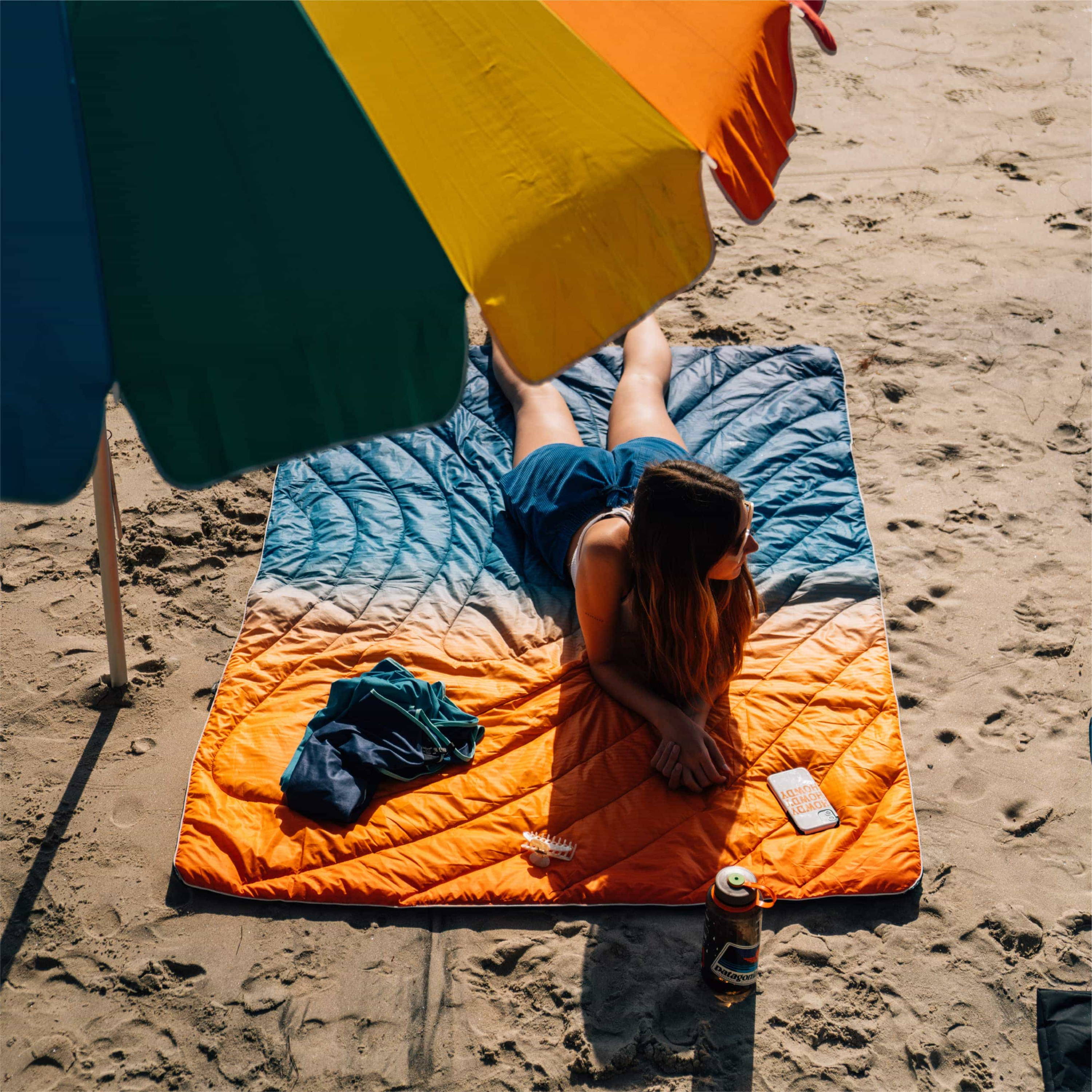 Woman Laying On Original Puffy Blanket Under Umbrella On The Beach