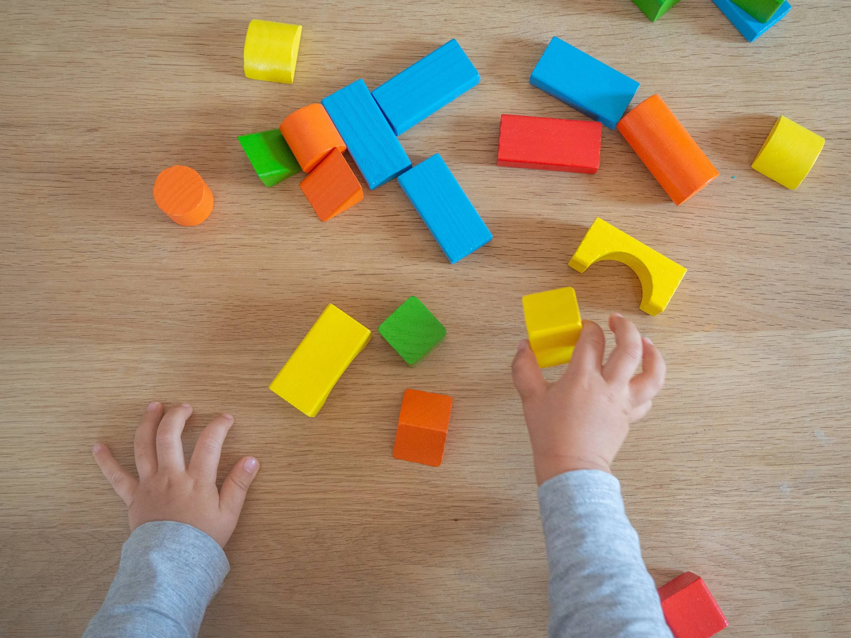 A child's hands playing with colorful wooden blocks