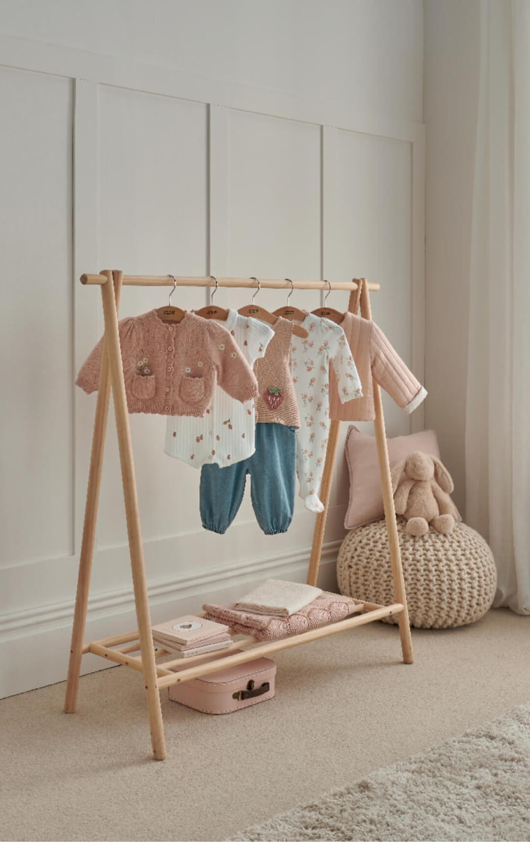 Children's clothing displayed on a wooden rack in a softly lit room.