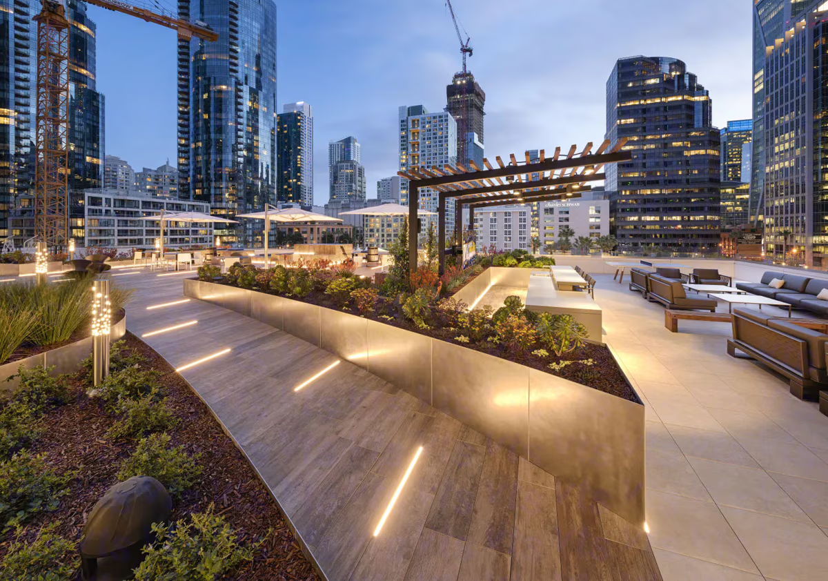 City rooftop terrace with modern seating and urban landscaping at dusk.