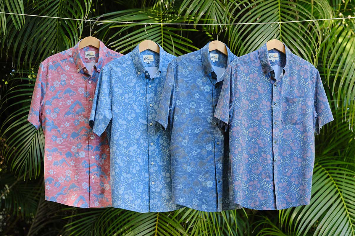 Four patterned short-sleeve shirts hanging against a tropical background.