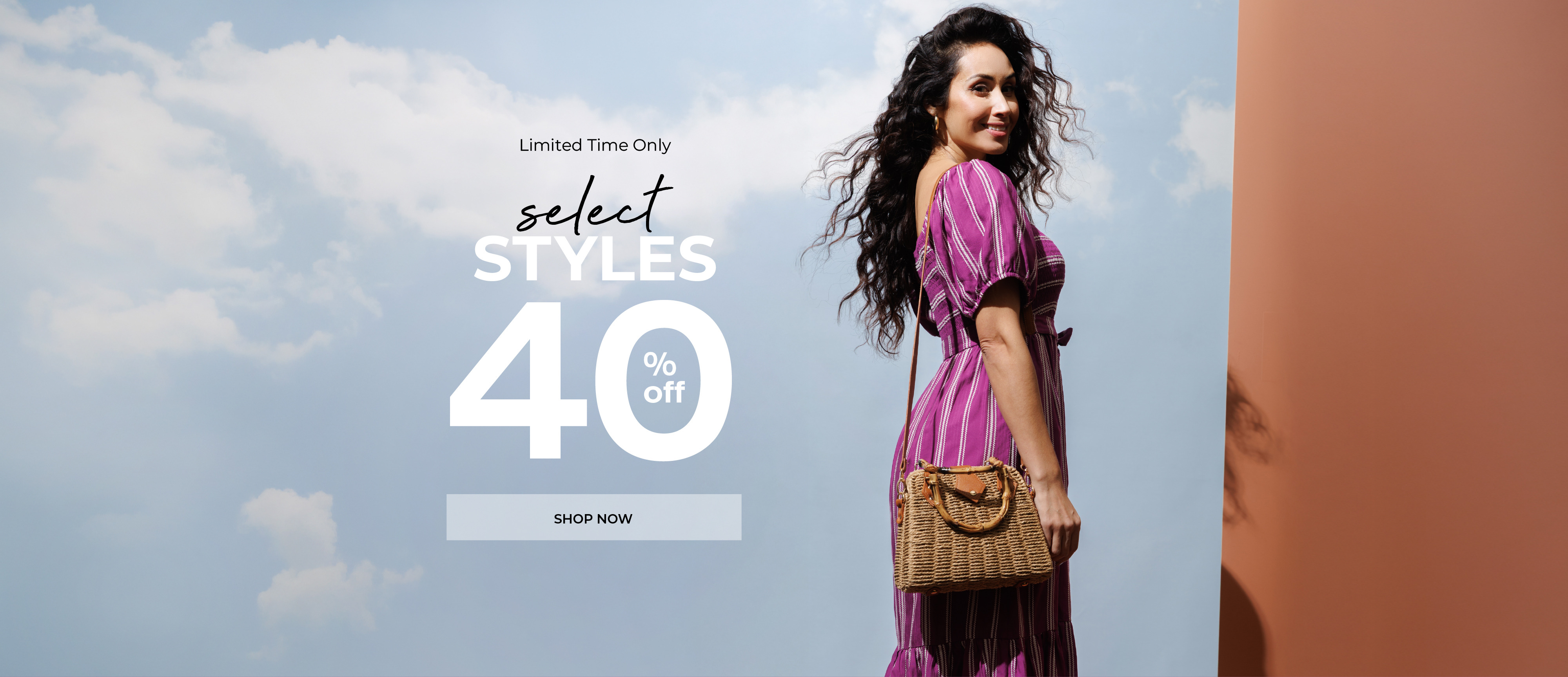 Woman in pink dress holding a bag against a blue sky background.