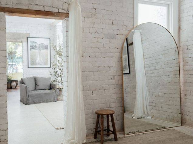 Brique apparente peinte en blanc et miroir en arc de cercle dans un vestiaire minimaliste chic