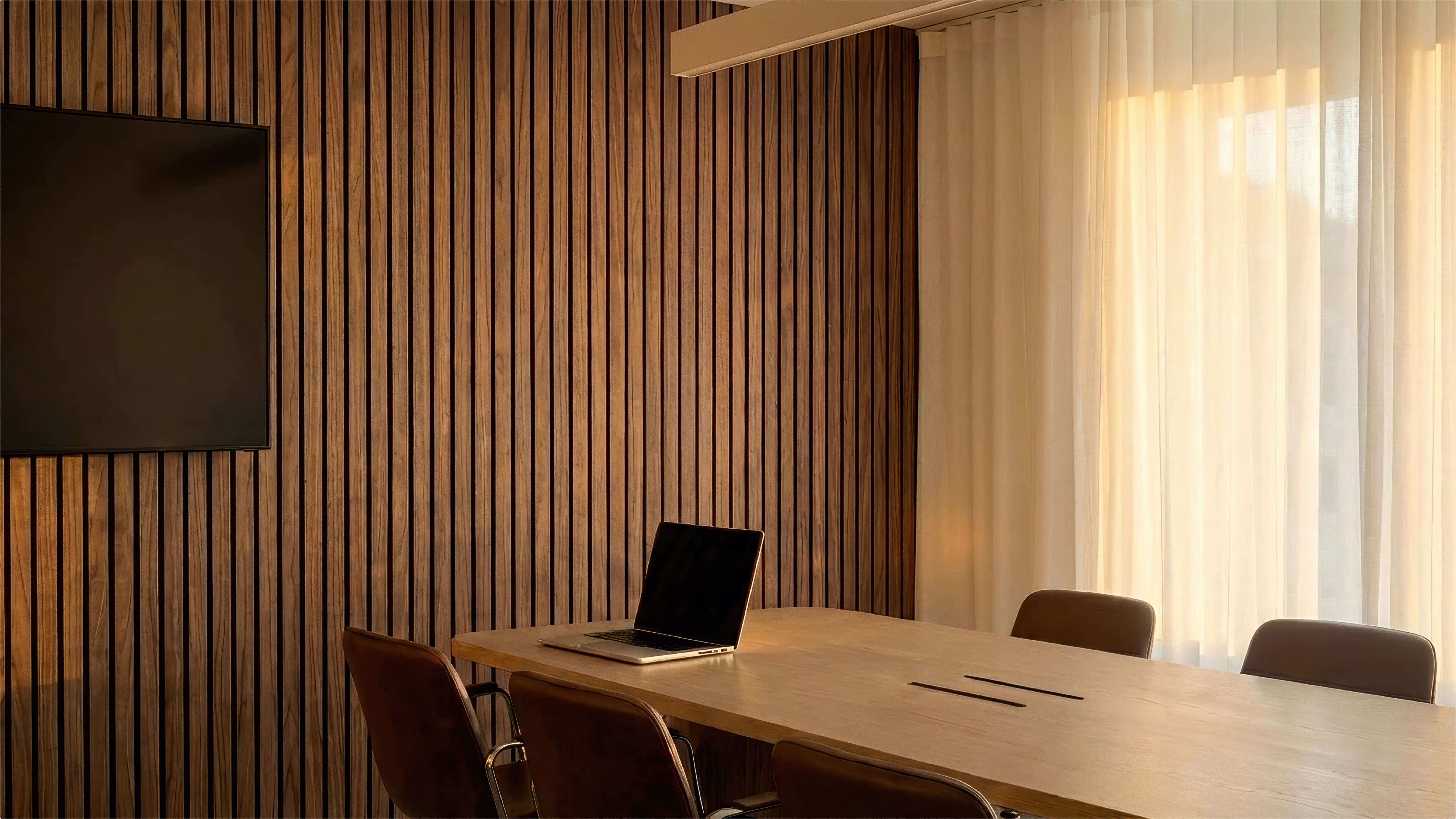 Modern conference room with a wooden wall, table, and laptop.