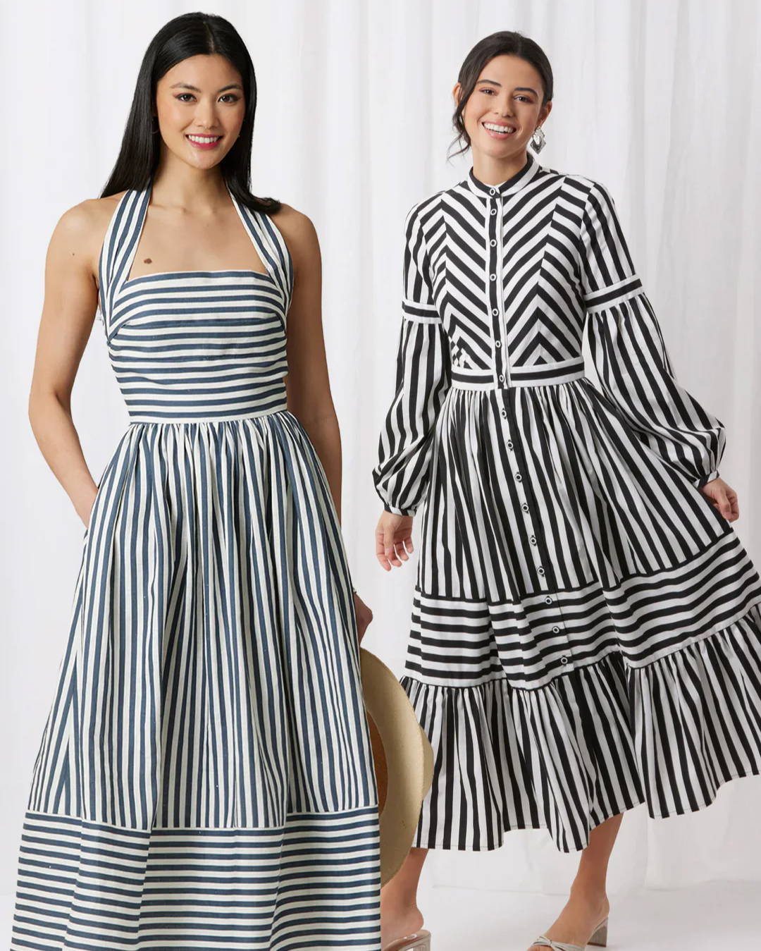 Two women wearing striped dresses in a studio setting.