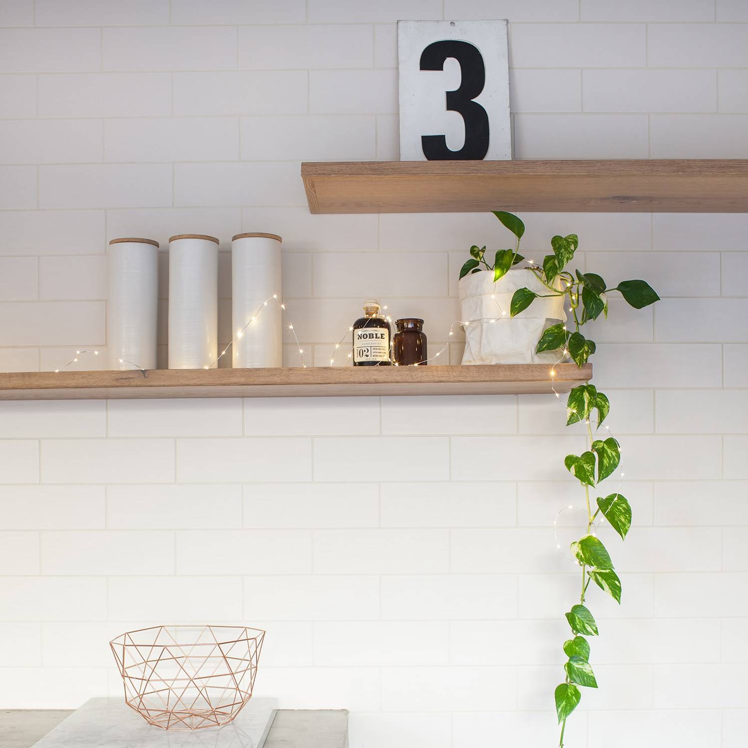 Shelf with jars and fairy lights and a plant in a kitchen.