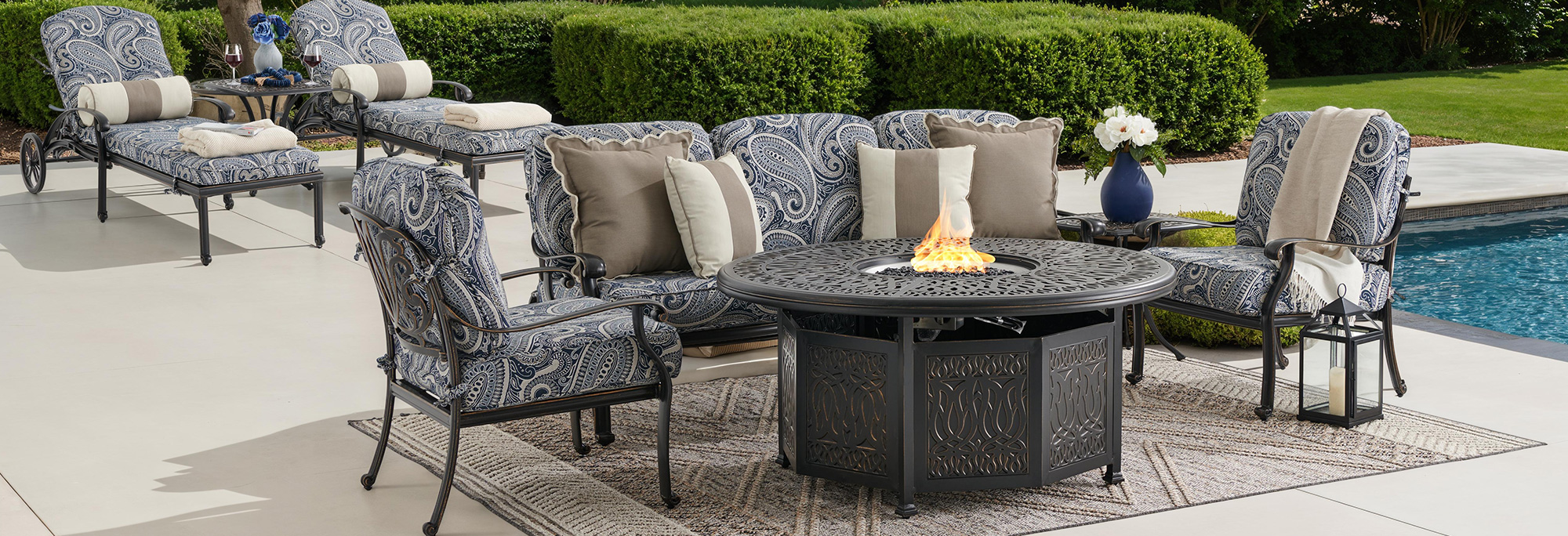 Outdoor seating area with cushions, table, and poolside view.
