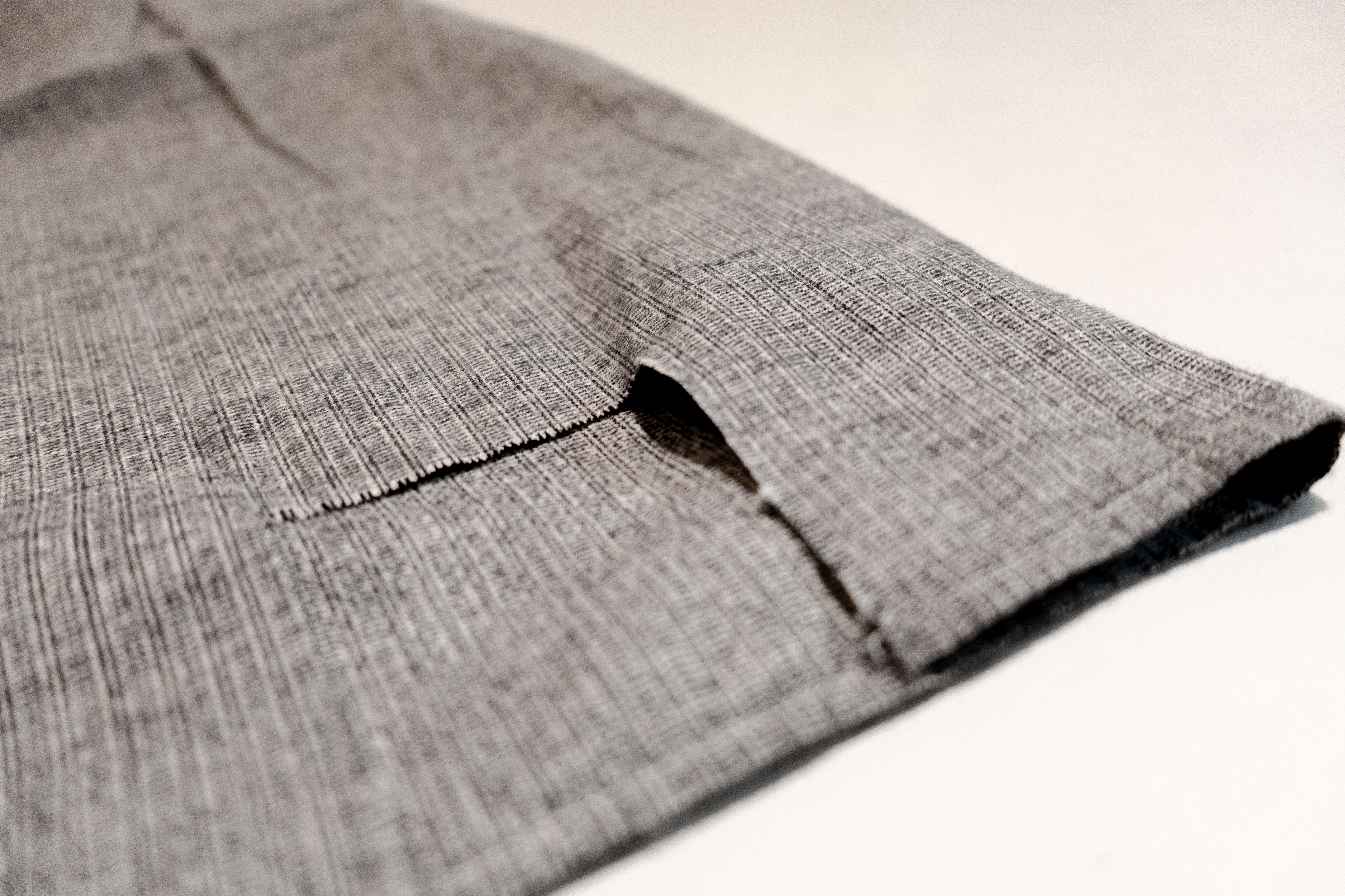 Close-up of a folded, textured gray fabric showing a seam.