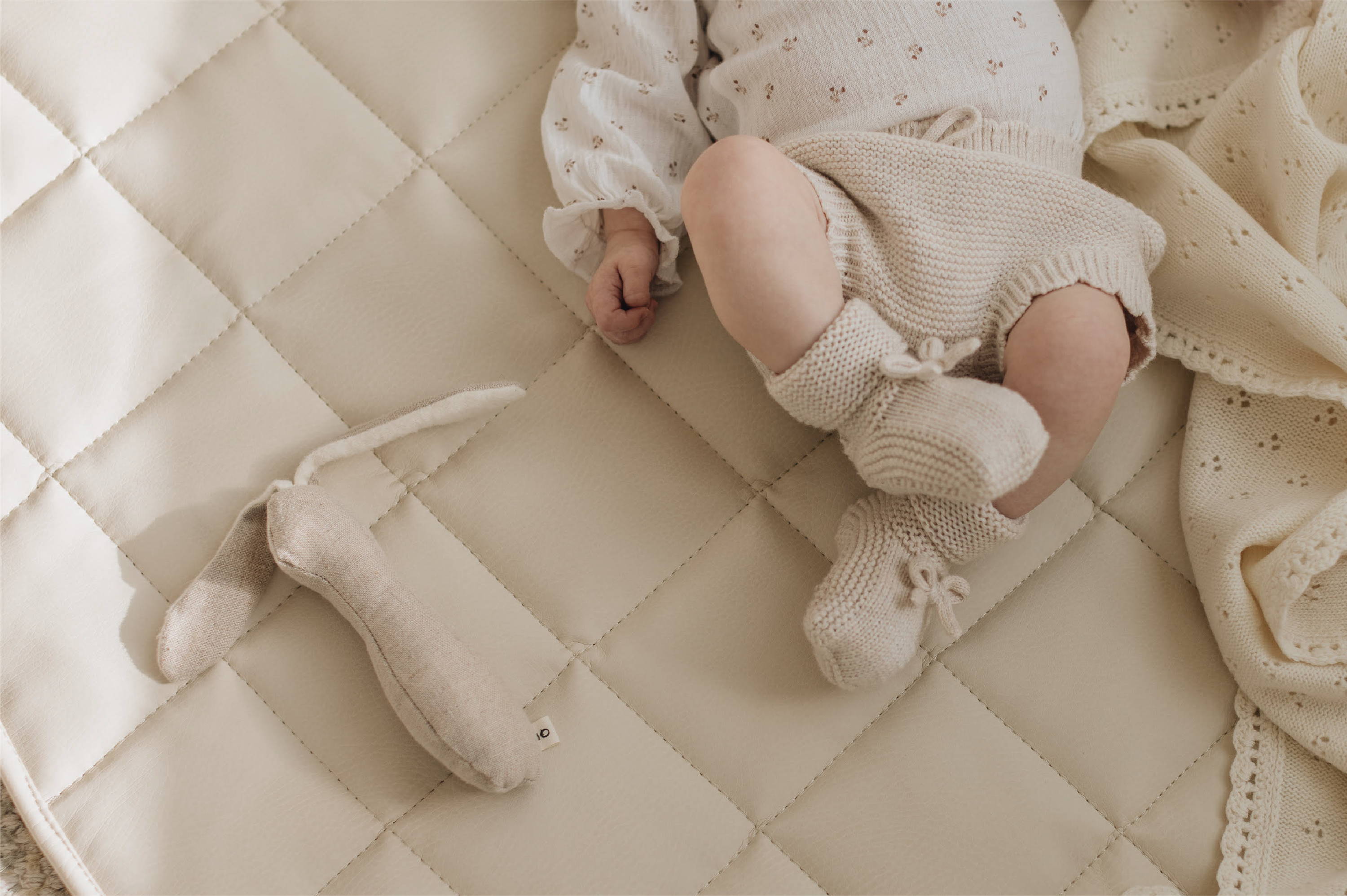 Baby items and baby laying on a Quilted Mini Mat