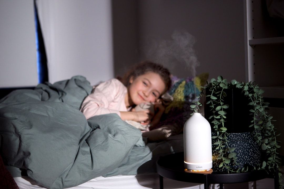 a girl is laying in bed with a humidifier