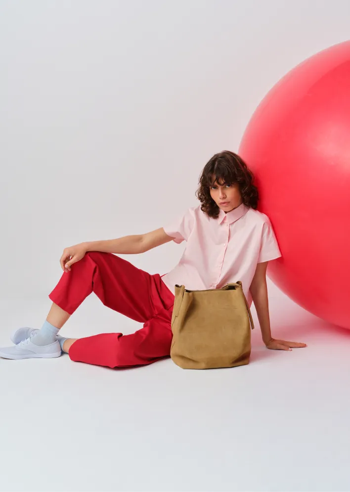 Person sitting next to a large pink ball, wearing casual clothing.