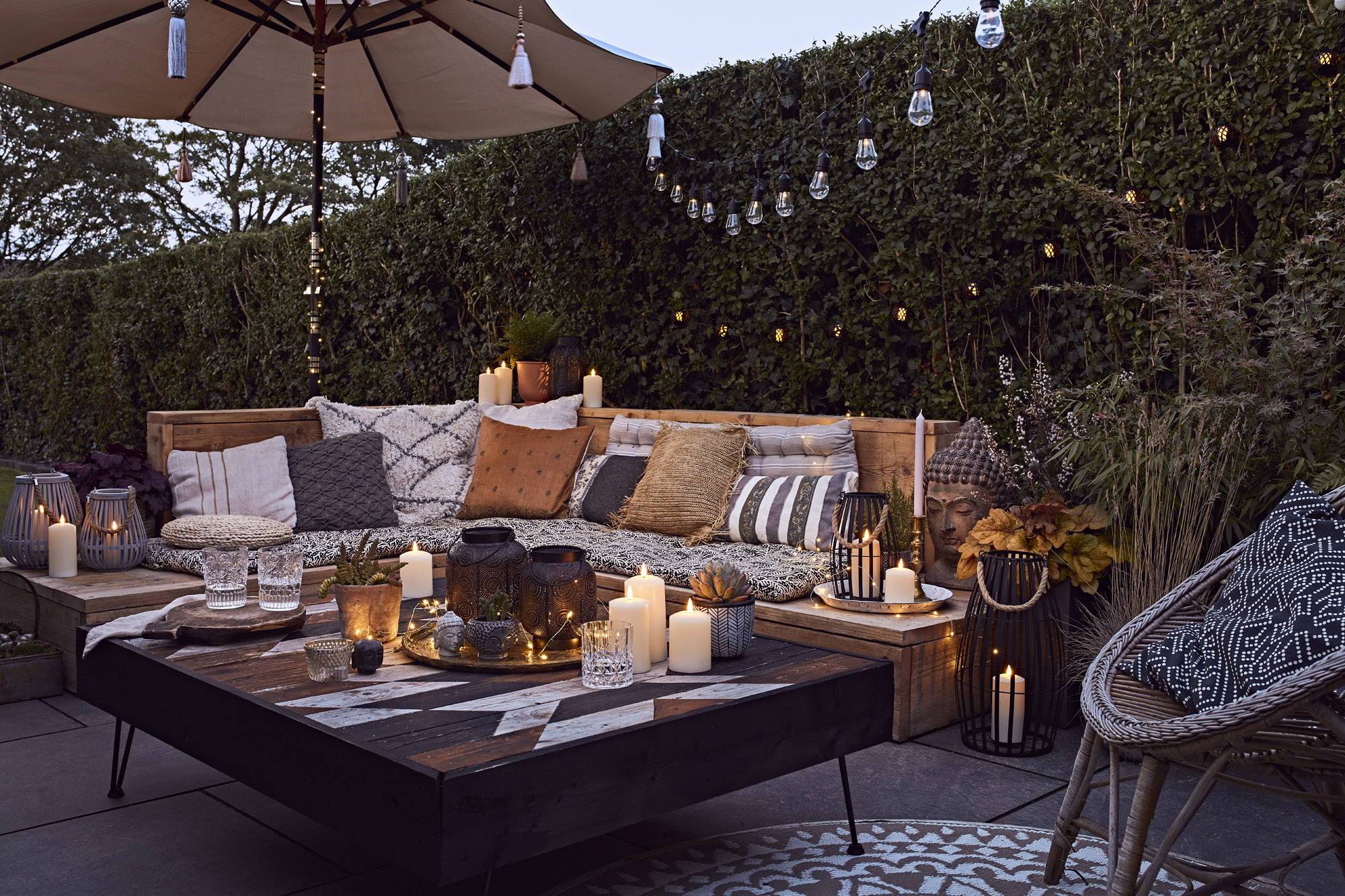 Outdoor garden seating area with festoons, LED candles and lanters.