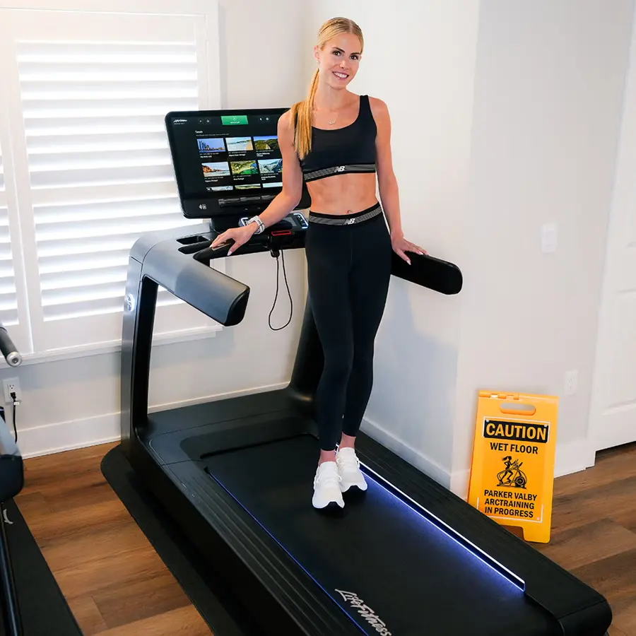 Woman standing on a treadmill in a bright indoor space.