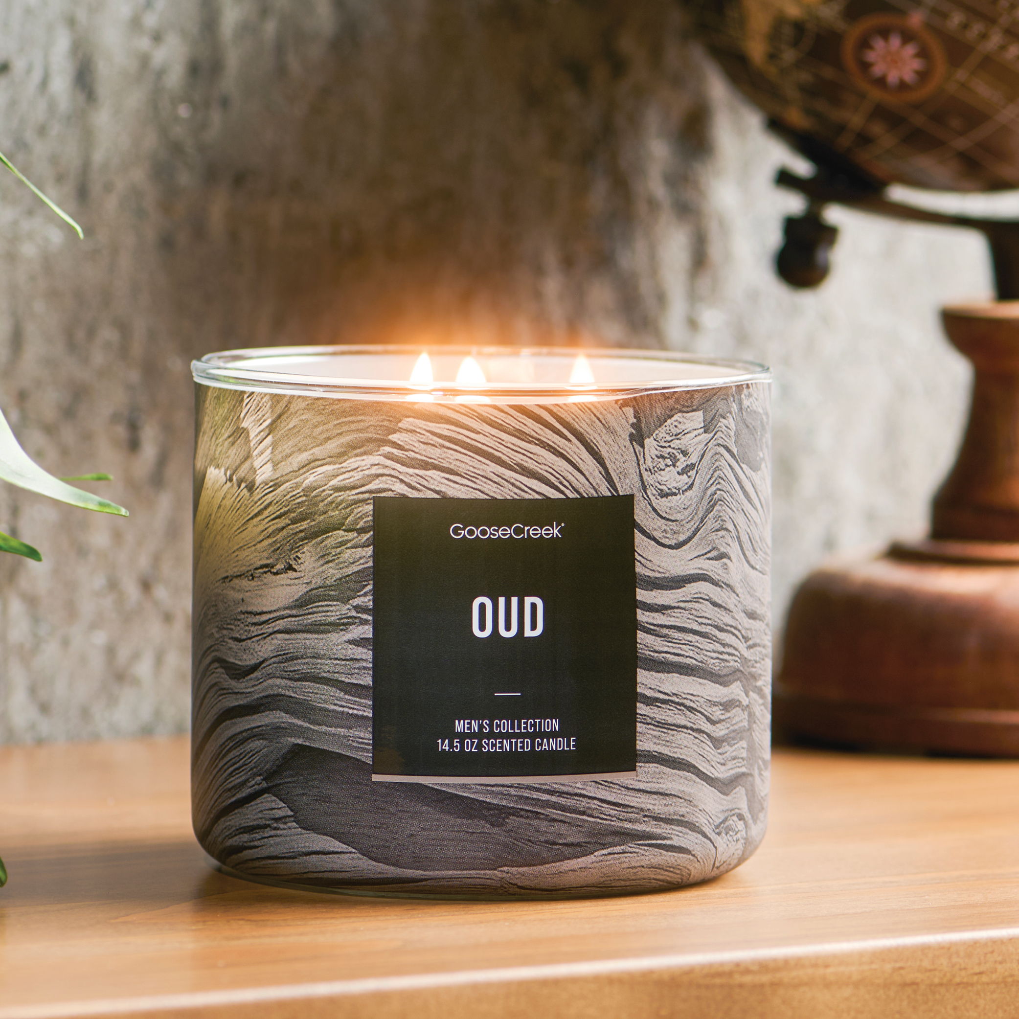 A lit candle in a decorative jar labeled 