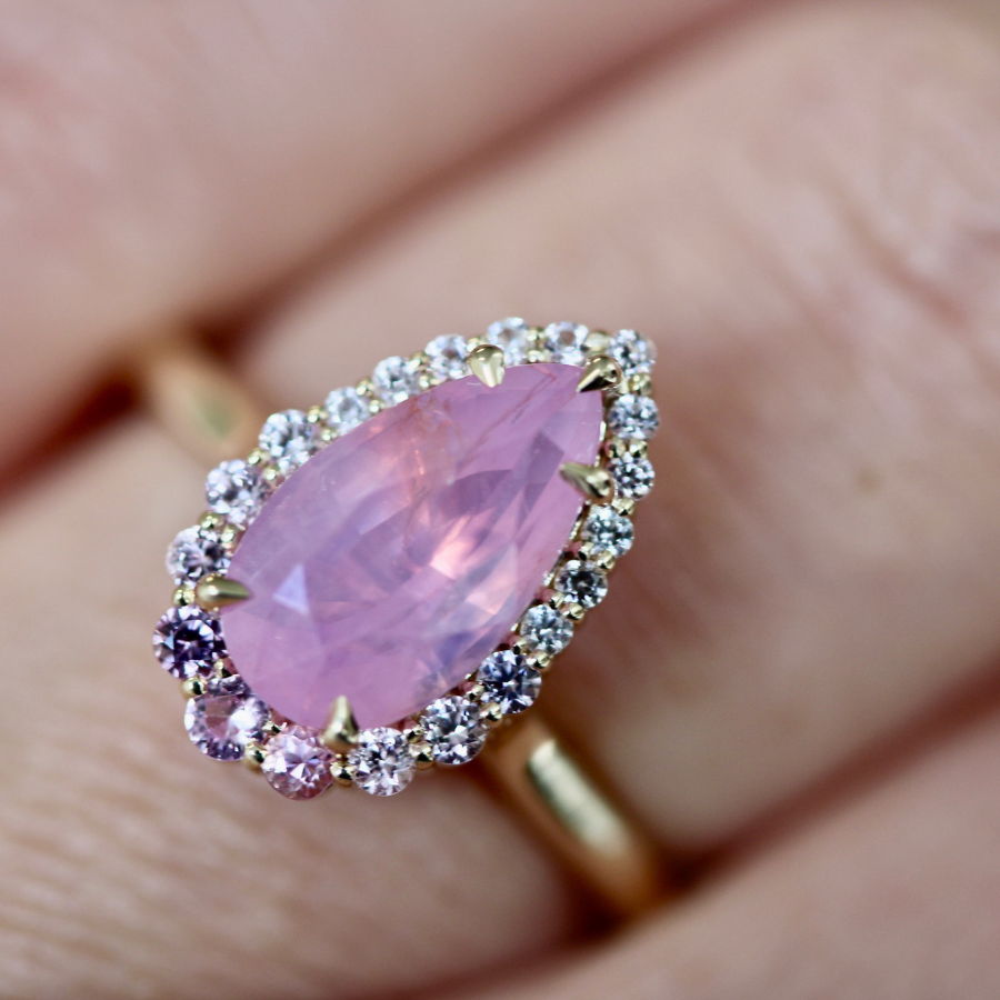 Pear shaped pink opalescent sapphire ring with diamond halo
