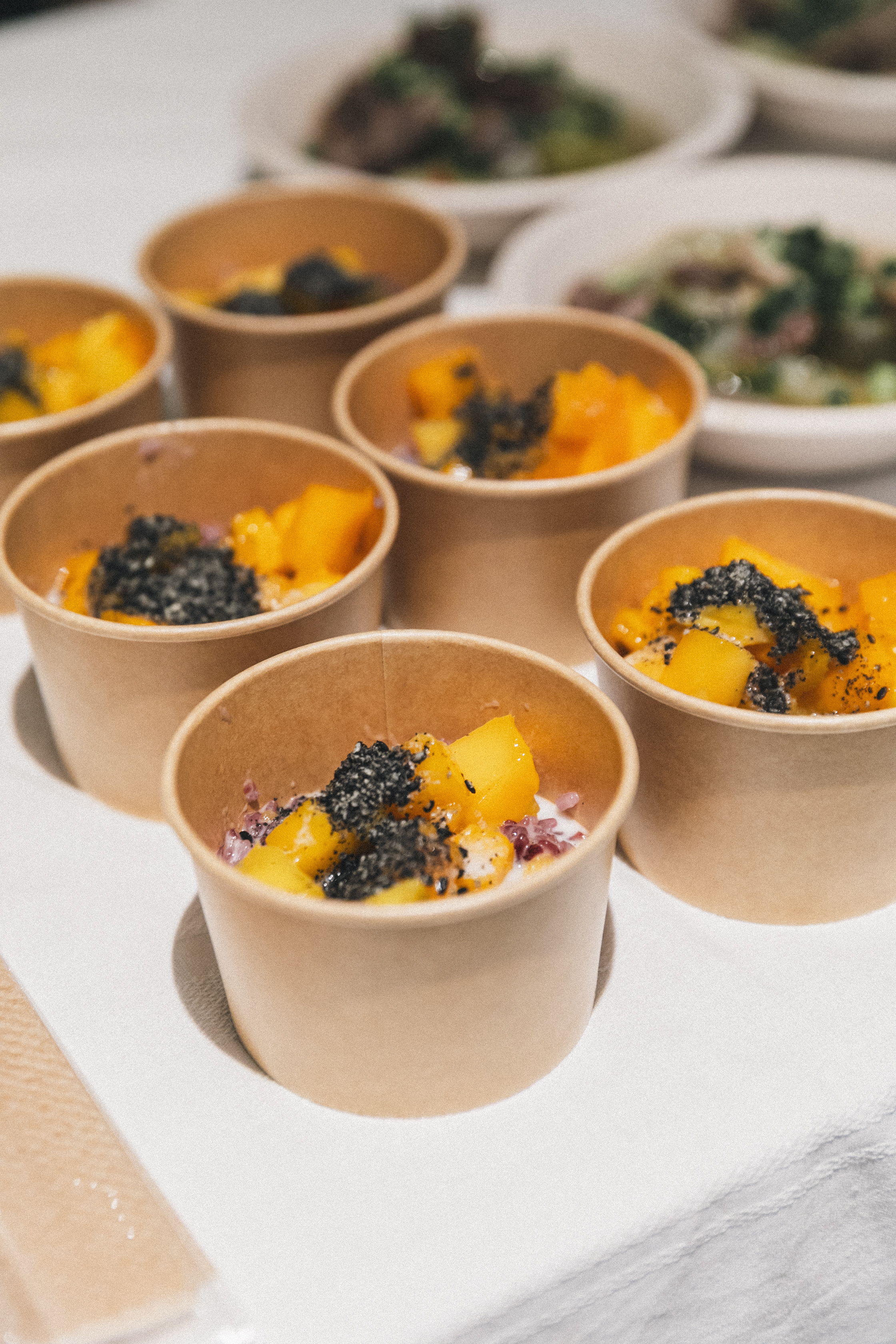 Multiple cups of colorful food garnished with seaweed.