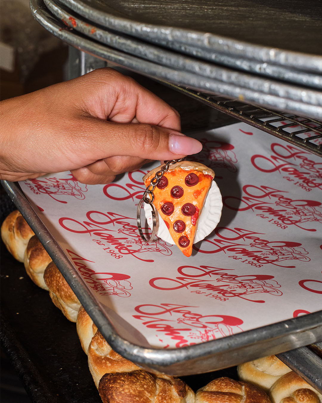A hand holding a small pizza slice on a tray.