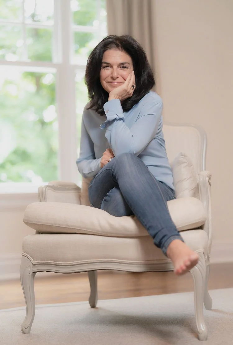 Smiling person sitting on a chair in a bright room.