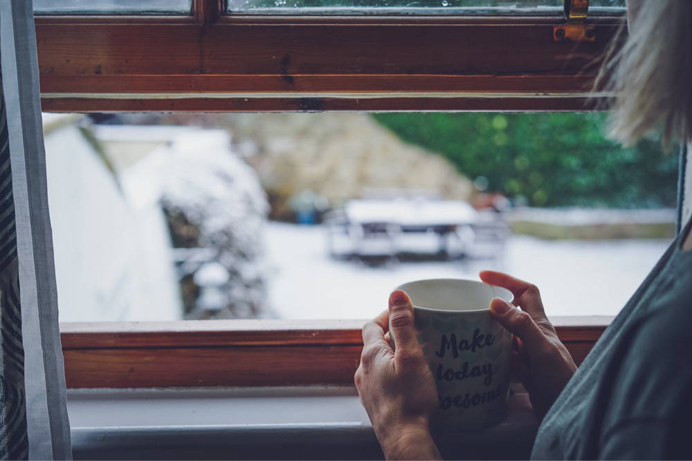 A woman sitting in front of a window with a chill drink in her hands