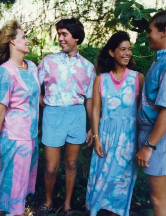 Four people in colorful matching outfits, smiling in a natural setting.