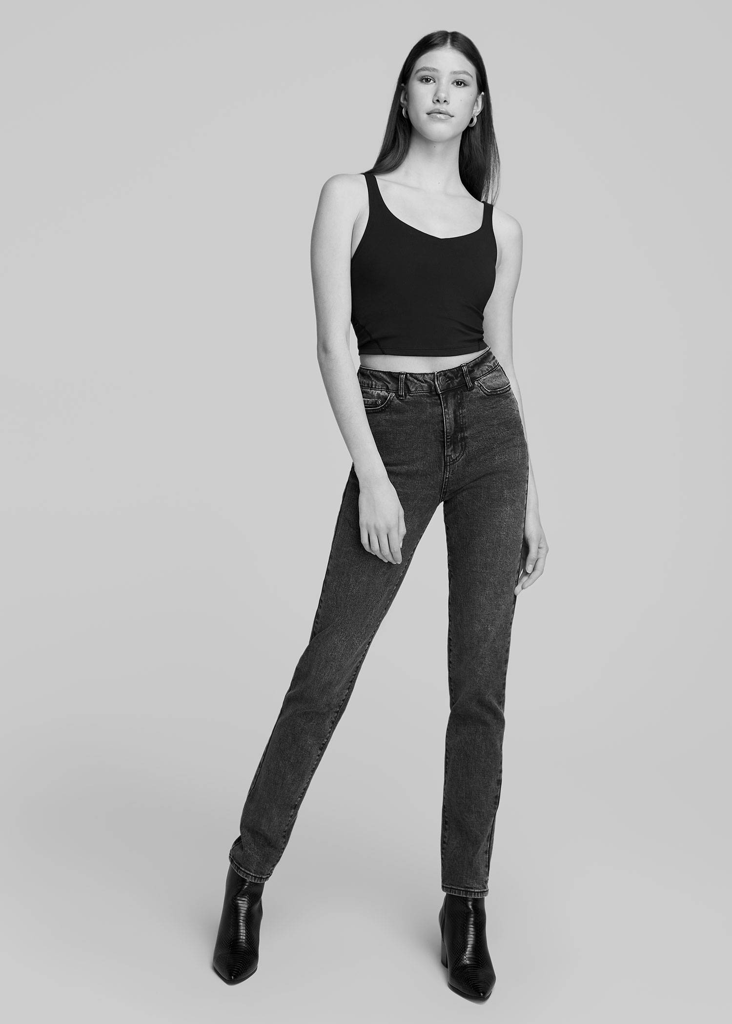 Tall woman wearing a black tank top and black jeans in black and white
