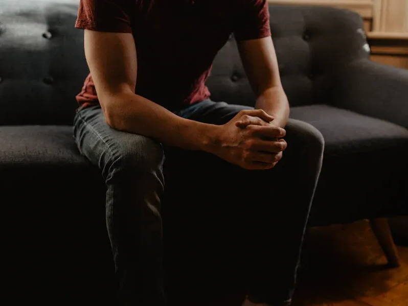 Man sitting on couch with fingers crossed