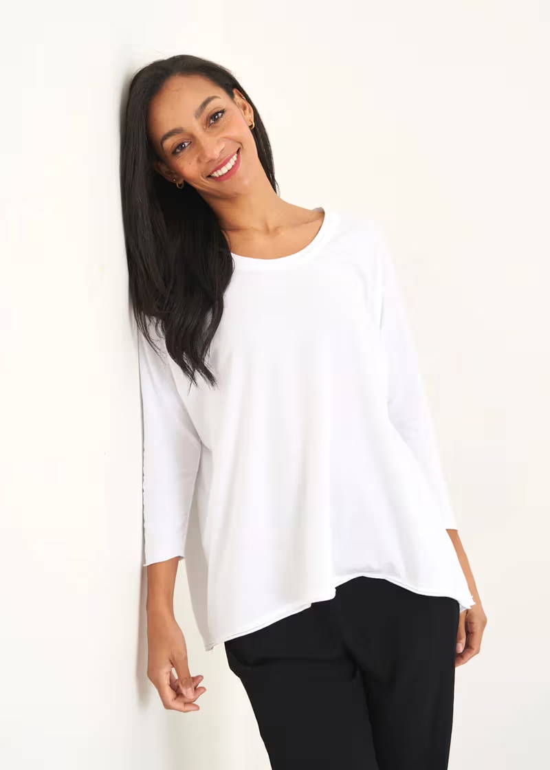 A model wearing a white overszied long sleeve top with black trousers