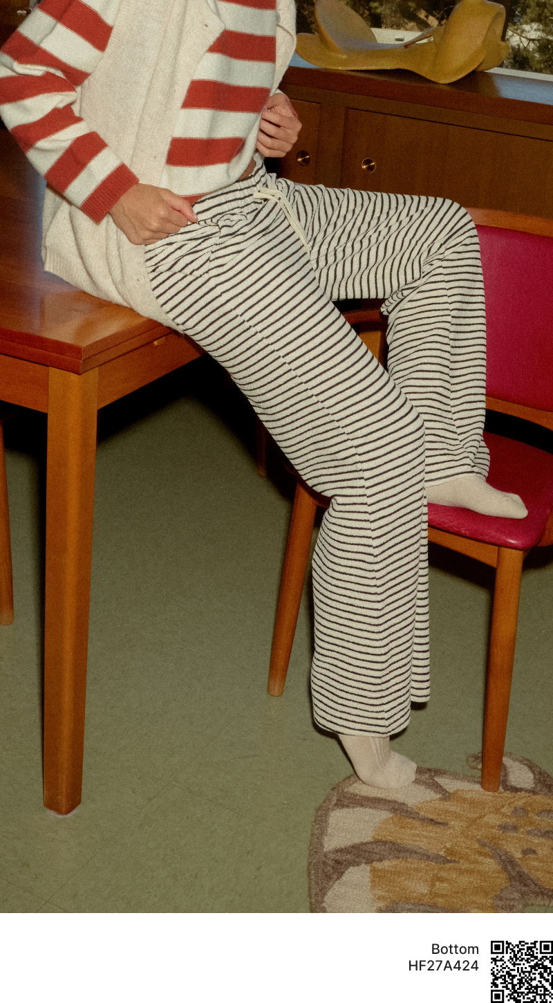Person sitting on a chair wearing striped pants and a striped sweater.