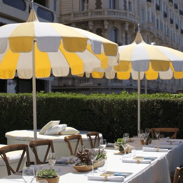 Yellow and white striped patio umbrellas shading outdoor dining tables for a resort-style patio dining space.