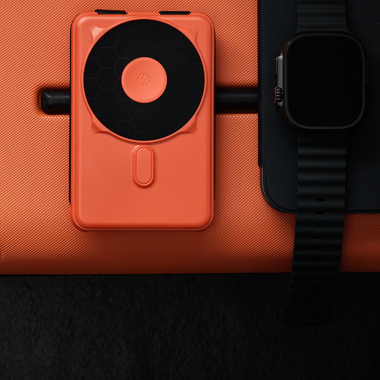 An orange device next to a smartwatch on a dark background.