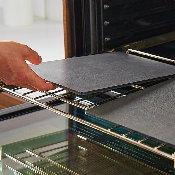 A hand places a Misen Oven Steel onto an oven rack next to another Misen Oven Steel, showing how they can fit neatly side-by-side.