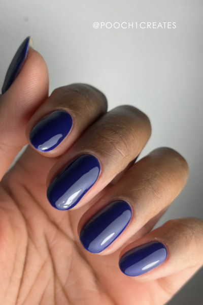 Close-up of hand with glossy dark blue nail polish.