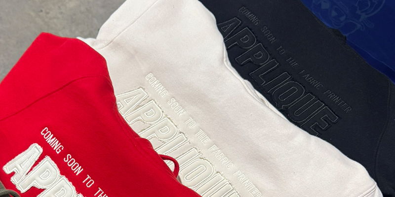 Apparel with clean tonal appliqué logo design stitched onto fabric with tonal thread showing smooth fabric overlays with defined edge stitching