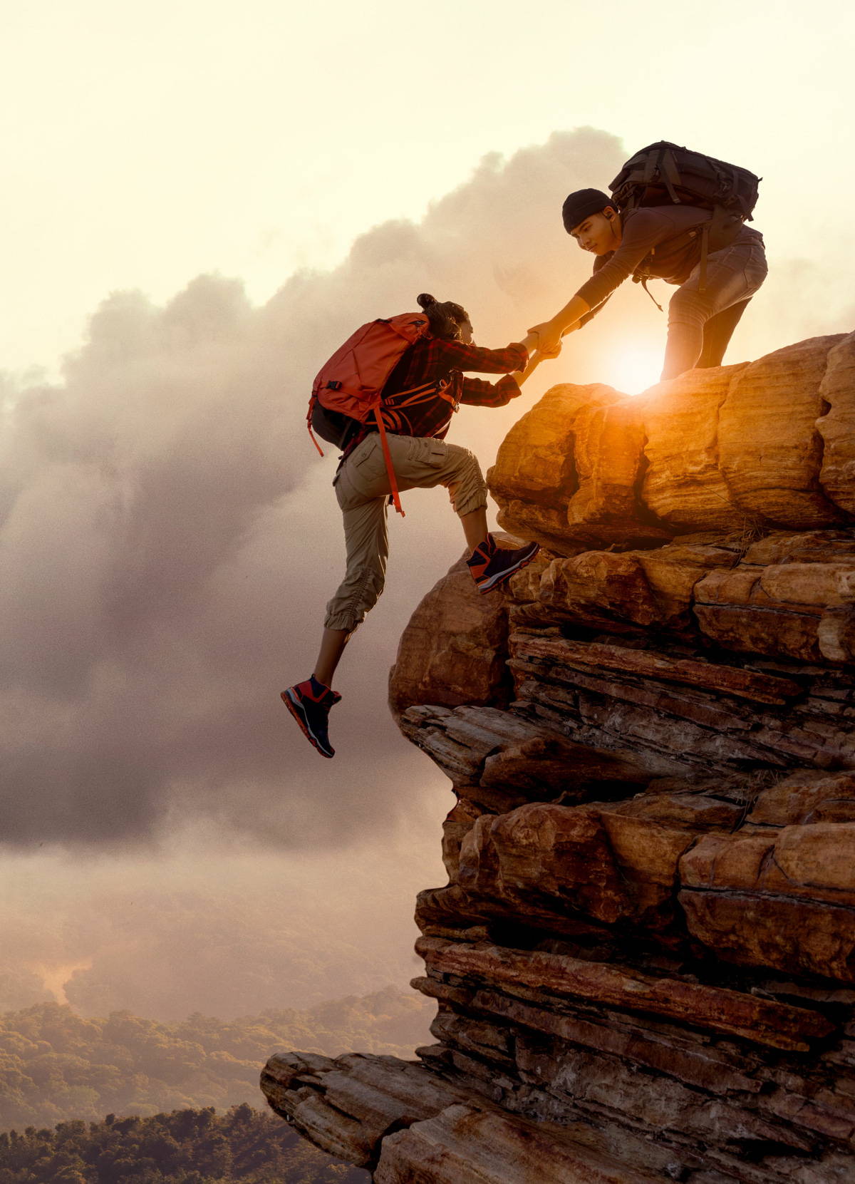 A mountain climber helping their partner up a ledge
