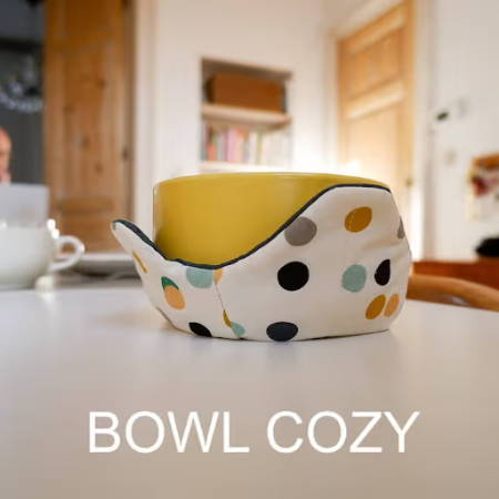 A bowl in a fabric bowl cozy made out of dotted fabric