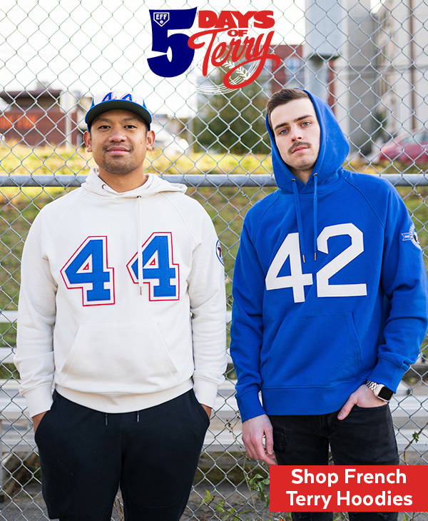Two men stand side by side in front of a chainlink fence. The man on the left is wearing a cream sweatshirt with the number 44 in royal blue and red felt, as well as a hat with a matching number 44 on it. The man on the right is wearing a royal blue sweatshirt featuring the number 42 in white felt with his hood pulled up. At the top of the image it says 