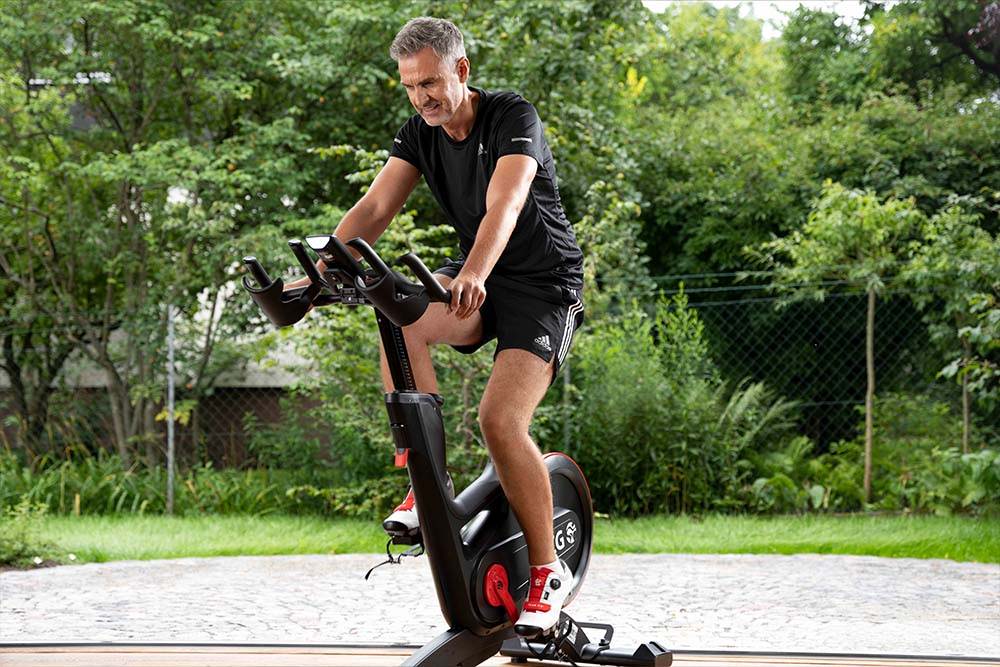 Man riding IC7 Indoor Cycle in backyard