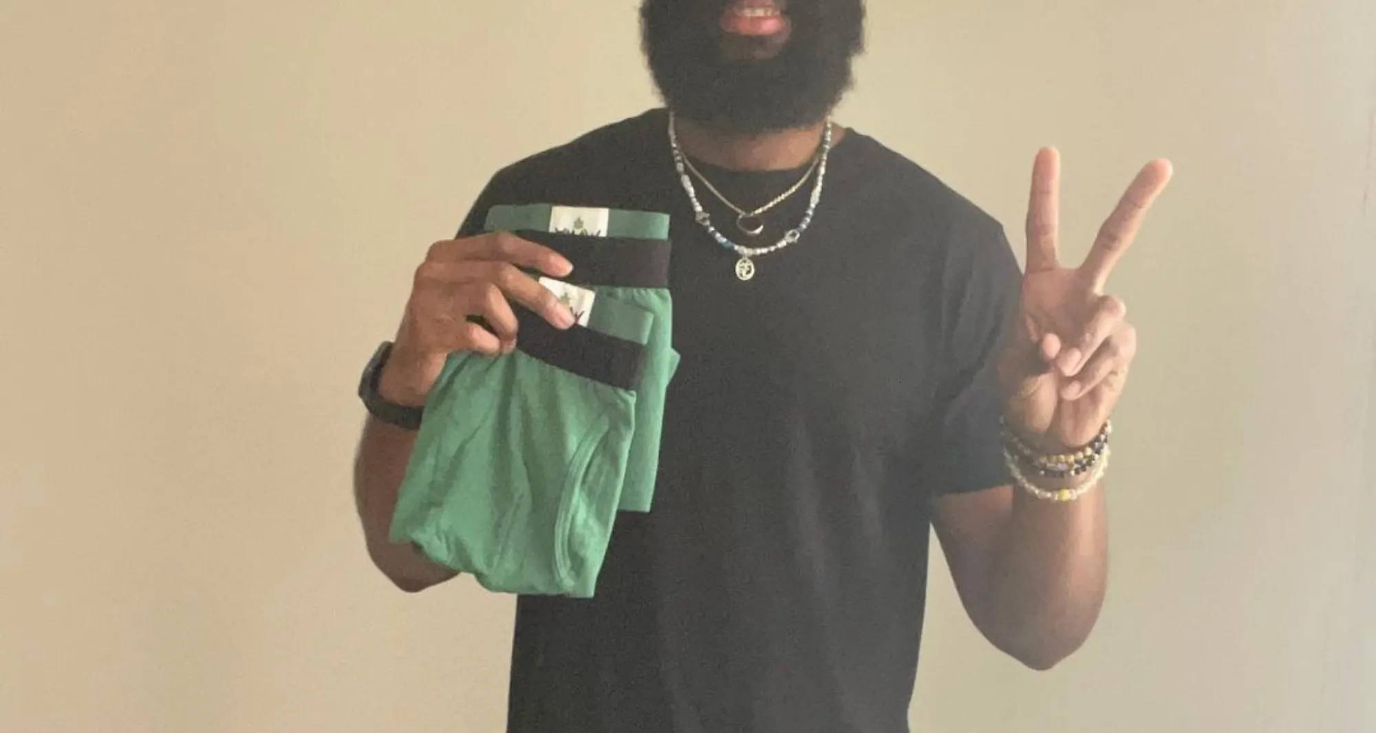 man wearing a black t-shirt and green boxer briefs holding up a peace sign and two other pairs of green undies