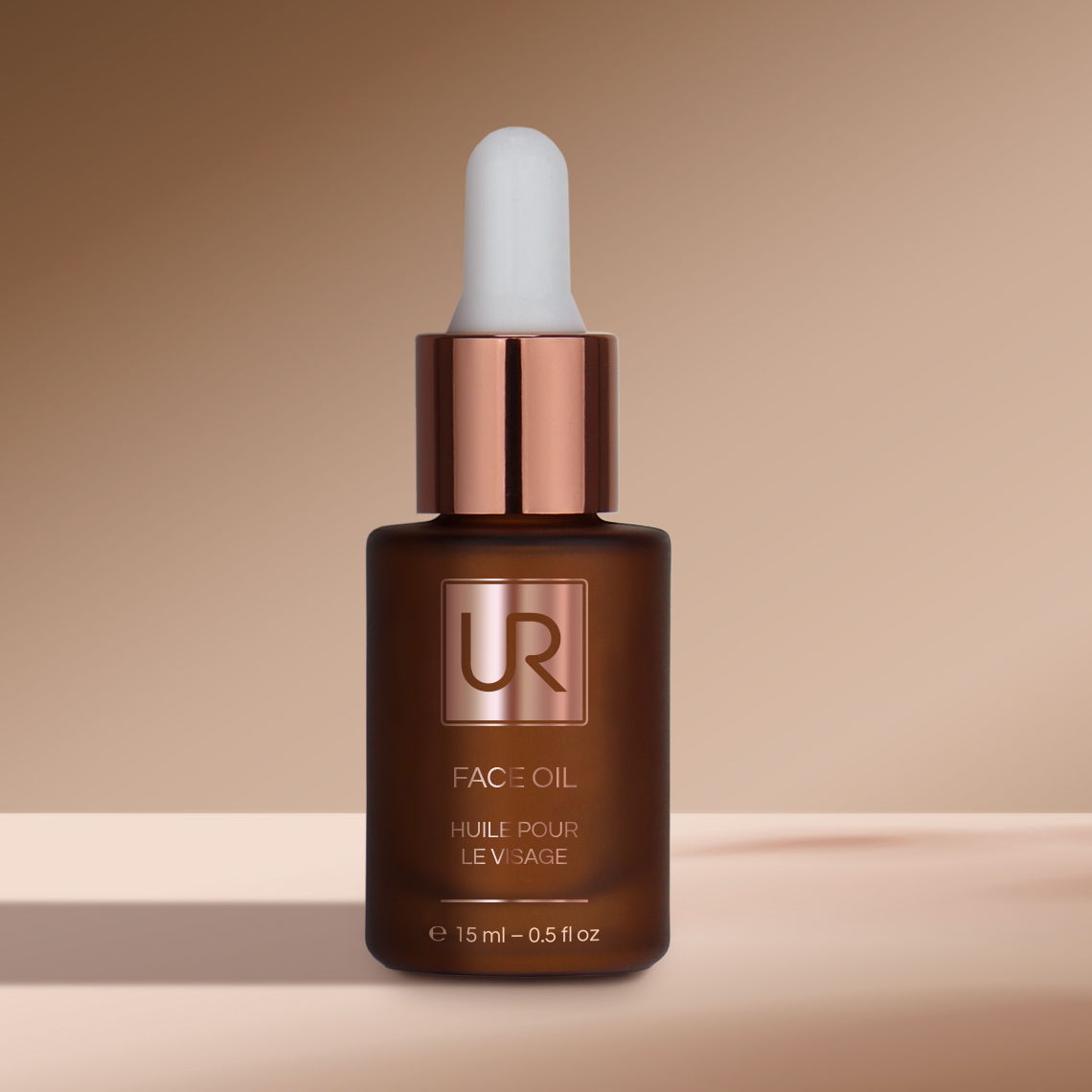 Brown glass bottle of facial oil with dropper on a beige background.